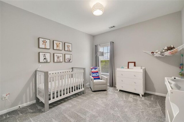 bedroom with baseboards, visible vents, a crib, and carpet