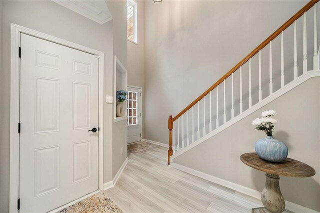 foyer entrance with baseboards, wood finished floors, stairway, and a towering ceiling