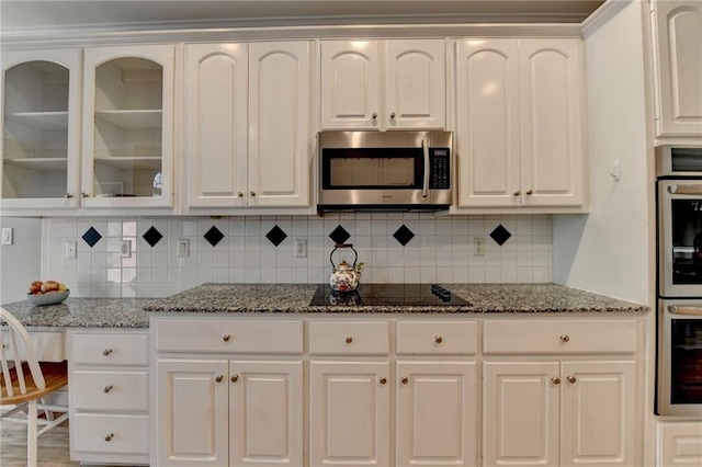 1901 Paper Birch Cv, Grayson, GA 30017 - kitchen featuring stainless steel microwave, black electric cooktop, glass insert cabinets, white cabinets, and backsplash