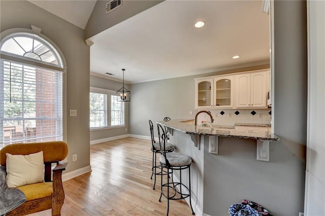1901 Paper Birch Cv, Grayson, GA 30017 - kitchen featuring a kitchen bar, glass insert cabinets, light stone counters, a peninsula, and tasteful backsplash