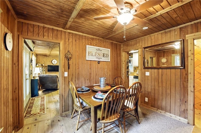 dining area featuring wooden walls, wooden ceiling, a ceiling fan, and light wood-style flooring
