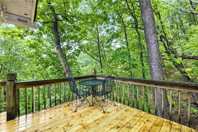 wooden terrace with a forest view and outdoor dining space