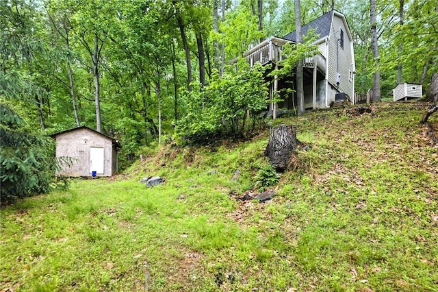 view of yard with a wooden deck, an outbuilding, a forest view, and a storage unit