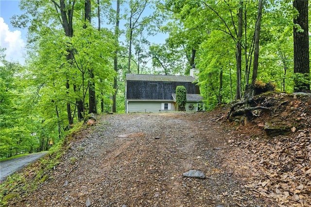 exterior space with a shingled roof and a chimney