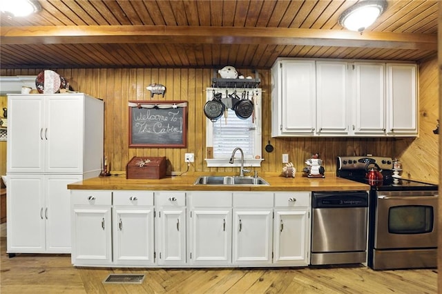 kitchen with beam ceiling, a sink, wood walls, stainless steel appliances, and wooden ceiling