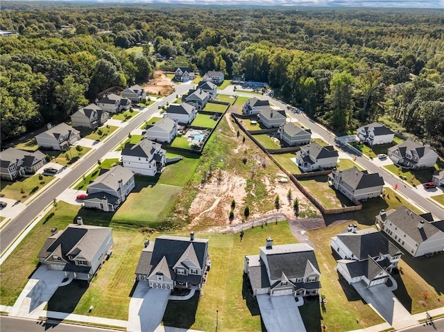 drone / aerial view featuring a wooded view and a residential view