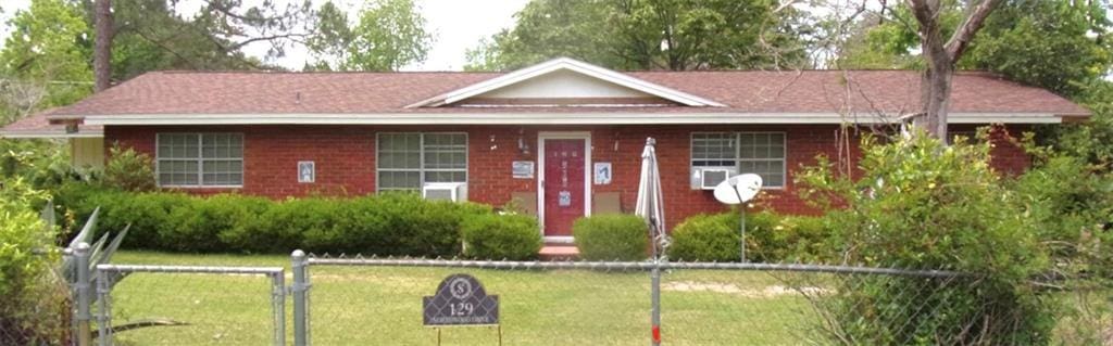 ranch-style house with a front lawn, fence, and brick siding