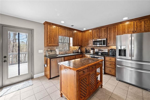 kitchen featuring appliances with stainless steel finishes, a sink, dark countertops, light tile patterned floors, and recessed lighting