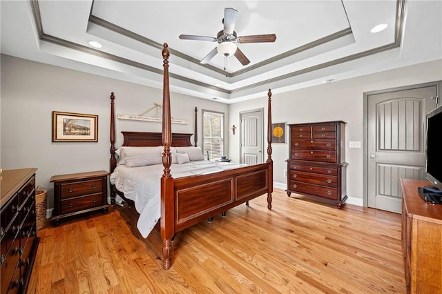 bedroom featuring a raised ceiling, crown molding, light wood-style floors, recessed lighting, and a ceiling fan