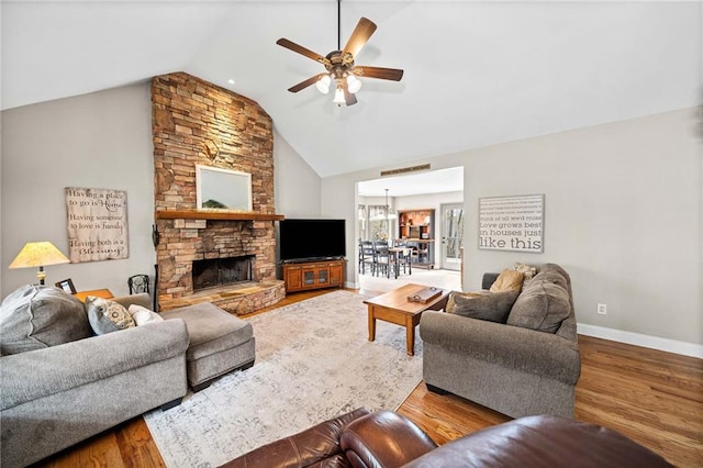 living area with ceiling fan, a fireplace, wood finished floors, baseboards, and high vaulted ceiling