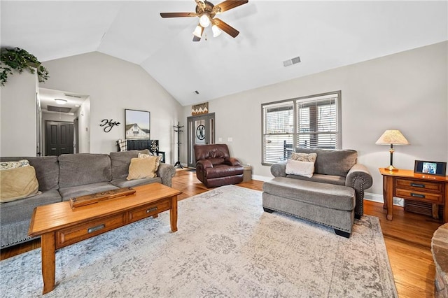 living room featuring ceiling fan, vaulted ceiling, light wood-style floors, and baseboards