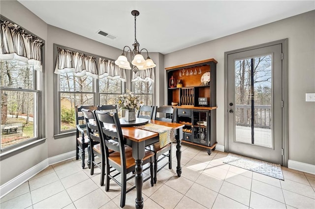 dining space with a chandelier, healthy amount of natural light, baseboards, and light tile patterned floors