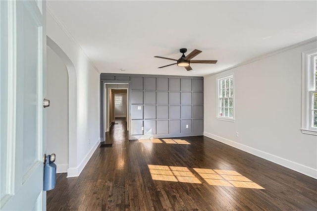 empty room featuring dark wood-type flooring, ceiling fan, and ornamental molding