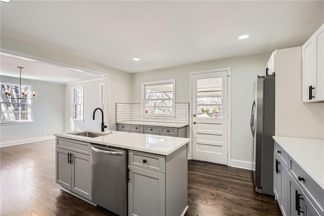 kitchen featuring sink, gray cabinetry, pendant lighting, stainless steel appliances, and a kitchen island with sink