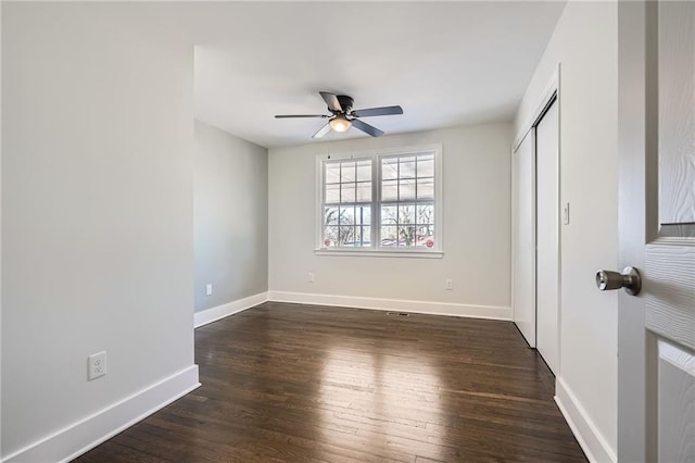 unfurnished bedroom with dark wood-type flooring, a closet, and ceiling fan