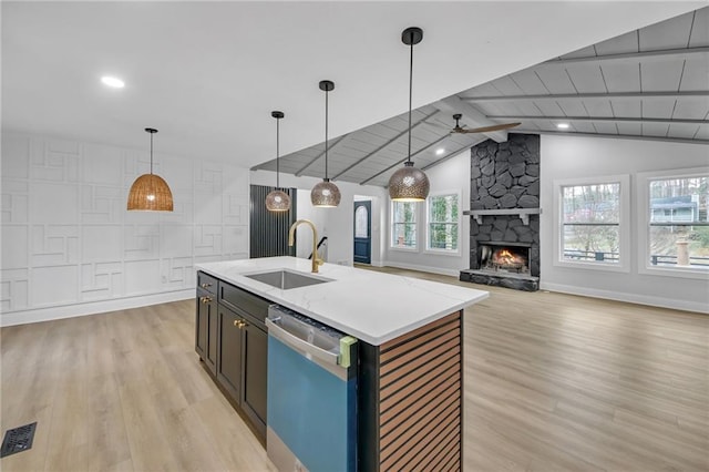 kitchen with light wood-style flooring, a sink, a fireplace, dishwasher, and vaulted ceiling with beams