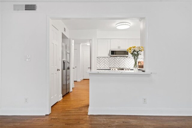 kitchen featuring blue cabinetry, light wood-type flooring, light stone counters, and stainless steel refrigerator