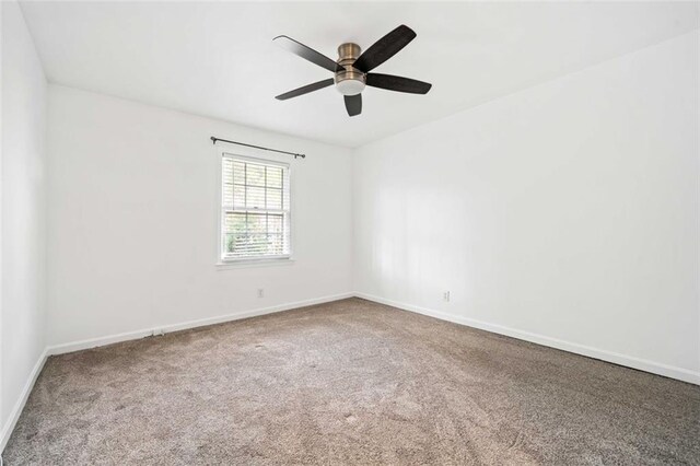 carpeted spare room featuring ceiling fan