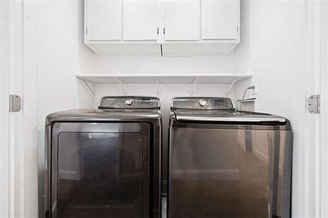 laundry room featuring separate washer and dryer and cabinets