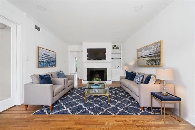 unfurnished living room with ornamental molding, hardwood / wood-style floors, and built in shelves