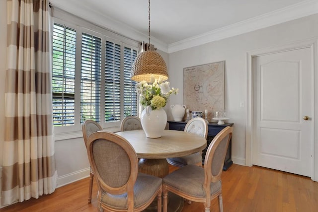 dining space with baseboards, crown molding, and light wood finished floors