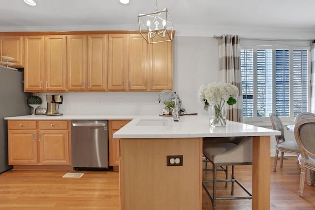 kitchen with a breakfast bar, light wood finished floors, stainless steel appliances, ornamental molding, and a sink