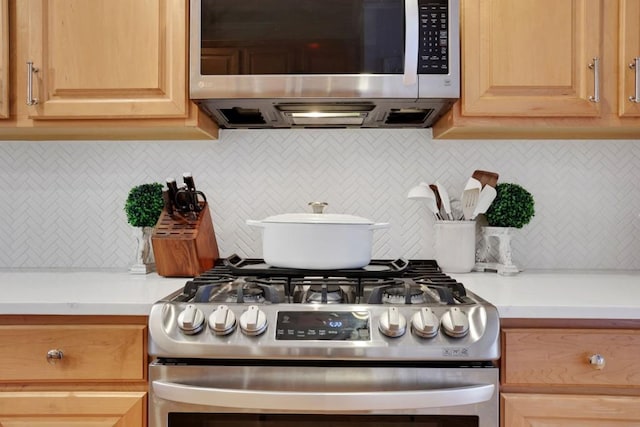 kitchen with light brown cabinets, light countertops, appliances with stainless steel finishes, and backsplash