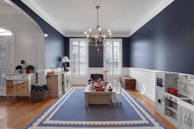 interior space featuring arched walkways, crown molding, a notable chandelier, wainscoting, and wood finished floors