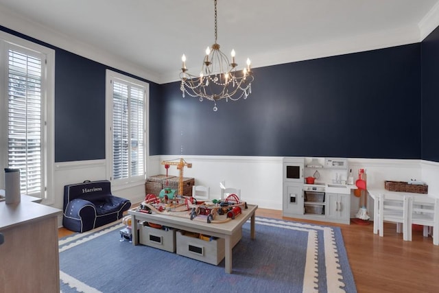 recreation room featuring a wainscoted wall, plenty of natural light, crown molding, and wood finished floors