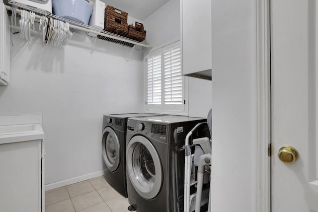 laundry area with cabinet space, light tile patterned floors, baseboards, and washer and clothes dryer