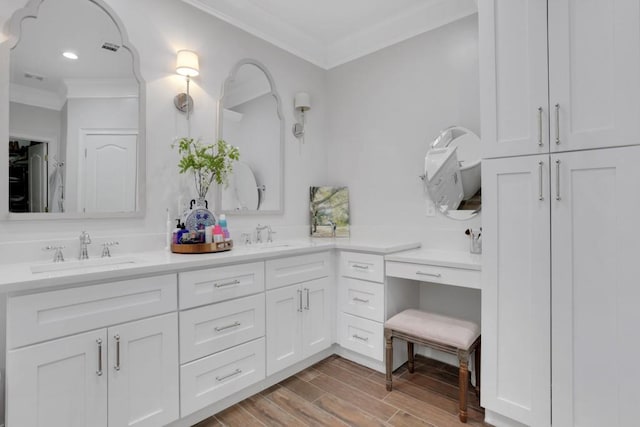 bathroom featuring wood finished floors, a sink, visible vents, double vanity, and crown molding