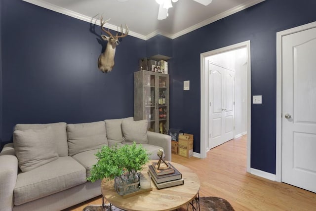 living room with crown molding, baseboards, ceiling fan, and wood finished floors