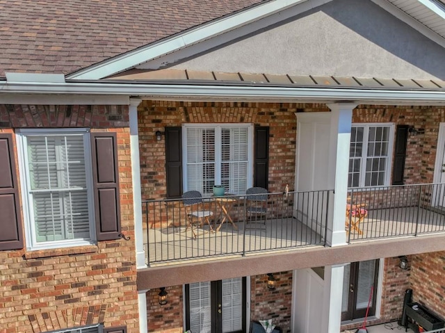 view of side of property featuring a shingled roof and brick siding