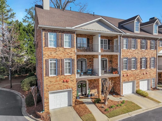 multi unit property with french doors, a chimney, a balcony, and concrete driveway