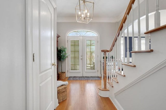 foyer entrance featuring french doors, ornamental molding, stairway, and wood finished floors