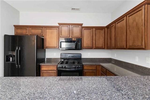 kitchen featuring dark stone countertops and black appliances