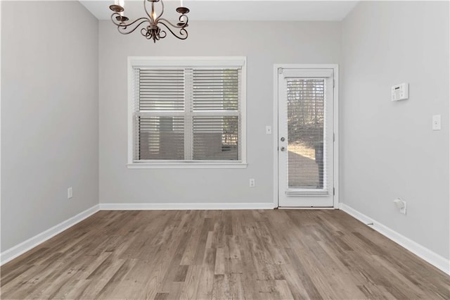 unfurnished dining area with light hardwood / wood-style flooring and a notable chandelier