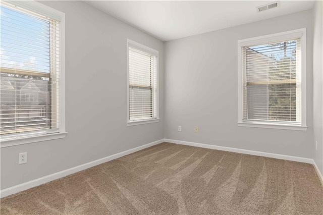 carpeted spare room featuring a healthy amount of sunlight