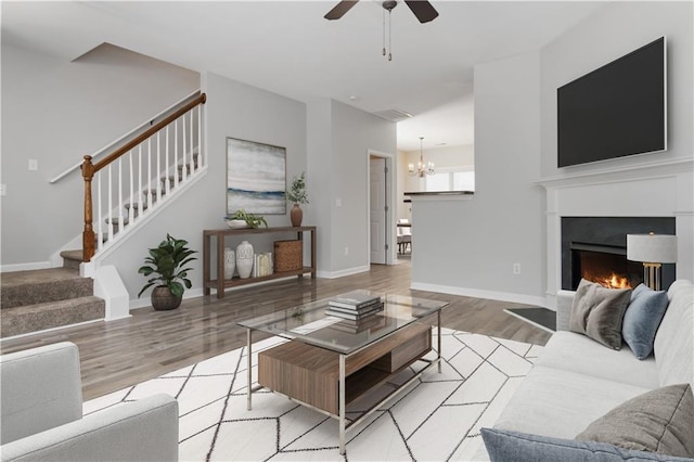 living room featuring ceiling fan with notable chandelier and light hardwood / wood-style flooring