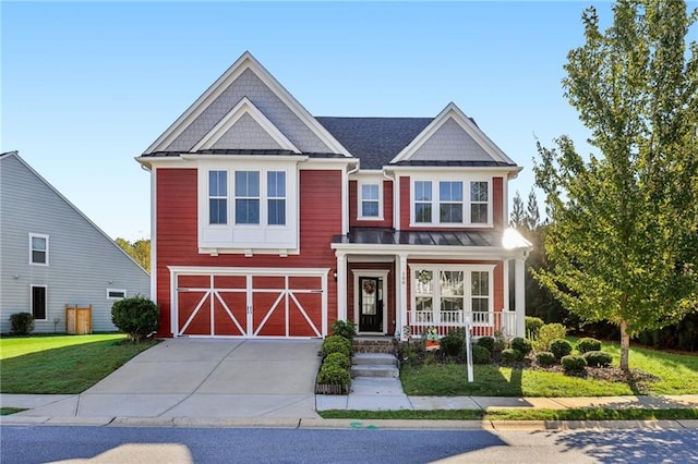 view of front facade with covered porch, a front yard, an attached garage, a barn, and driveway