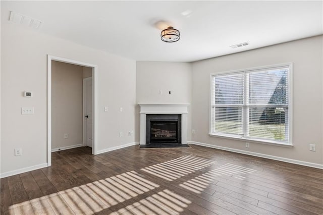 unfurnished living room featuring visible vents, baseboards, wood-type flooring, and a fireplace with flush hearth