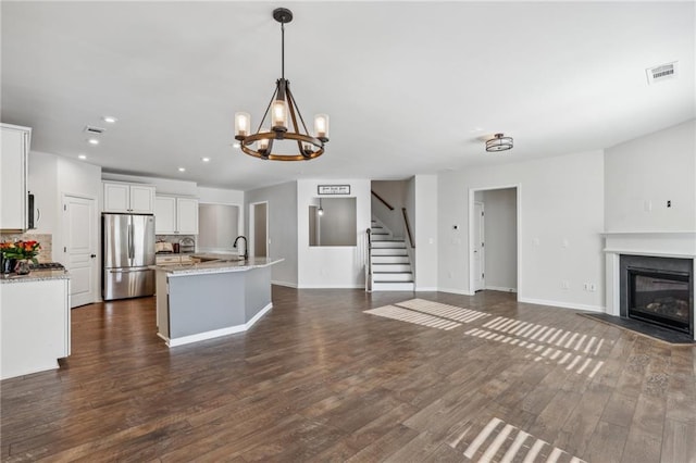 unfurnished living room with a chandelier, dark wood-style floors, visible vents, and recessed lighting
