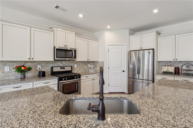 kitchen with stainless steel appliances, tasteful backsplash, visible vents, and a sink