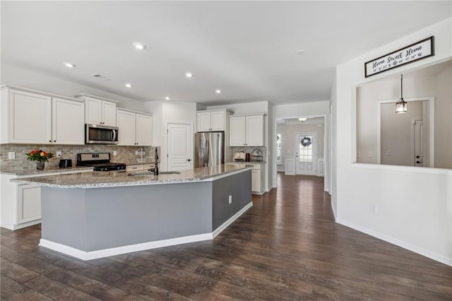kitchen featuring stainless steel appliances, white cabinets, a sink, and decorative backsplash