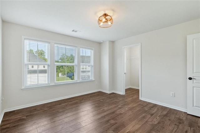 spare room featuring baseboards, dark wood finished floors, and visible vents