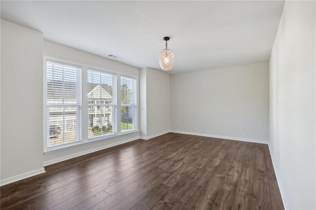 empty room featuring dark wood-type flooring, baseboards, and visible vents