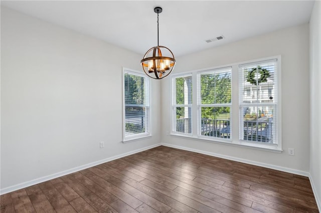 unfurnished room featuring an inviting chandelier, baseboards, dark wood finished floors, and visible vents