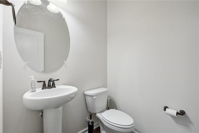 half bath featuring toilet and baseboards