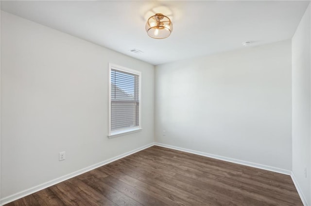 unfurnished room featuring visible vents, baseboards, and dark wood-style floors
