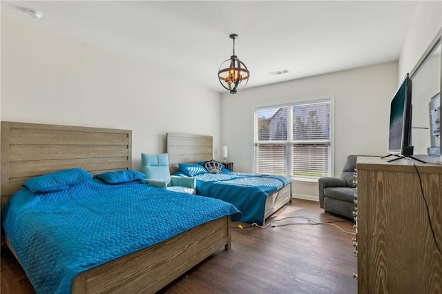 bedroom featuring baseboards, wood finished floors, a notable chandelier, and visible vents
